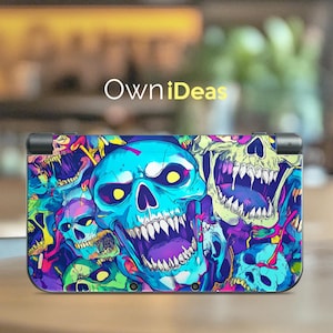 May include: A colorful, skull-themed skin for a handheld gaming device. The design features multiple skulls in shades of blue, purple, green, and yellow, with the text "OwniDeas" in white. The device is shown on a wooden surface.