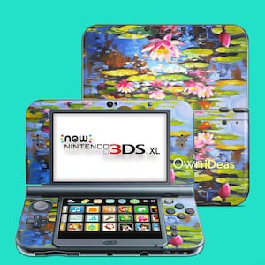 May include: A blue and green Nintendo 3DS XL console with a water lily design. The console has a touch screen and buttons. The text "new NINTENDO 3DS. XL" is displayed on the screen. The text "OwnIdeas" is displayed on the back of the console.