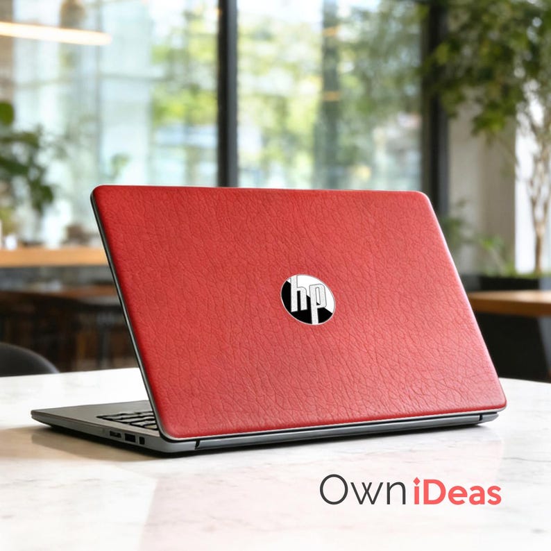 K&ouml;nnte beinhalten: Roter Laptop mit dem HP-Logo auf dem Deckel. Der Laptop ist auf einer wei&szlig;en Oberfl&auml;che ge&ouml;ffnet. Der rote Deckel des Laptops hat ein strukturiertes Aussehen. Der Text "OwniIdeas" ist unten im Bild sichtbar.