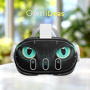Puede incluir: Auriculares de realidad virtual negros con un diseño de ojos de gato con ojos turquesa brillantes. Los auriculares tienen detalles en blanco y el texto "OwniDeas" en amarillo. Los auriculares tienen tres lentes circulares pequeños.