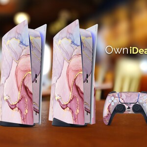 May include: Two pink and gold marble patterned console covers and a matching pink and gold marble patterned controller for a gaming console. The console covers are open and the controller is laying on a table. The text "OwnIdeas" is in the background.