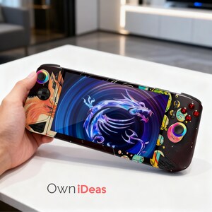 Può includere: Una console di gioco portatile con una grafica di drago vibrante sullo schermo. La console presenta pulsanti colorati e un design decorativo sui lati, tenuta in mano. Il testo "Own iDeas" è visibile in basso.