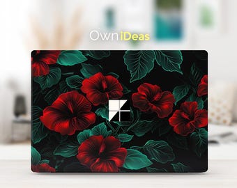 May include: Laptop skin with a floral design featuring red hibiscus flowers and green leaves on a black background. The skin has a cutout for the laptop's webcam and a Microsoft logo.