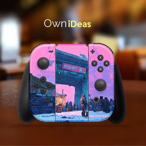 May include: A custom Nintendo Switch controller with a vibrant pink and purple cityscape design. The controller features black buttons and joysticks, with the text "OwniDeas" at the top. The design includes a Japanese-style gate and figures.
