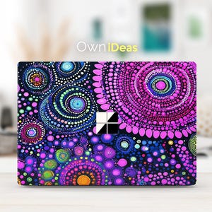 May include: A laptop skin with a colorful abstract design featuring a variety of circles and dots in shades of pink, purple, blue, and green on a black background. The design is reminiscent of a mandala or dot painting style. The skin is compatible with Microsoft Surface laptops.