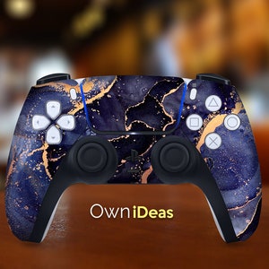 Puede incluir: Un mando de PlayStation 5 negro y dorado con un patrón de mármol. El mando tiene el logotipo de PlayStation y el texto "OwnIdeas".