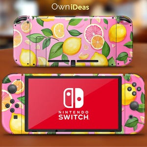 以下が含まれることがあります： ピンクのニンテンドースイッチコンソールスキンで、レモンとグレープフルーツのデザイン。スキンはピンクの背景に黄色のレモン、緑の葉、ピンクのグレープフルーツのスライスが描かれています。ニンテンドースイッチのロゴが画面に表示されています。