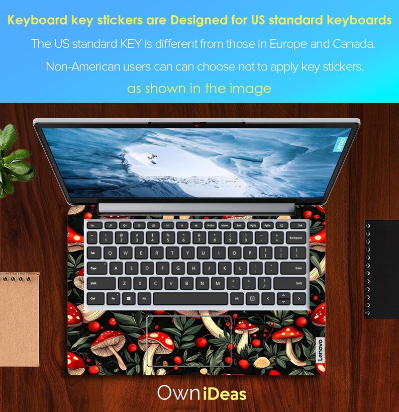 May include: Laptop with a keyboard skin featuring a pattern of red mushrooms, green leaves, and berries on a black background. The laptop screen displays a snowy landscape. The keyboard has white keys. The text "Own iDeas" is visible.
