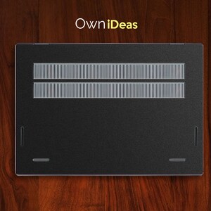 May include: Black laptop computer with a silver grill on the back. The laptop is on a wooden surface.