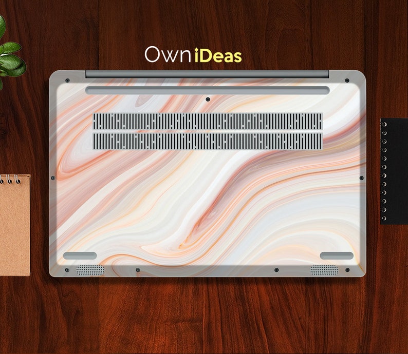 May include: A laptop with a white marble design on the lid. The design features swirls of white, brown, and orange. The laptop has a silver trim and a black vent.