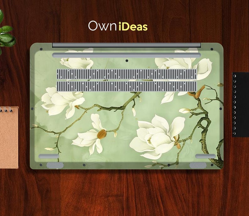 May include: A laptop skin with a floral design featuring white magnolia blossoms on a light green background. The design includes a branch with leaves and buds. The skin has the text "OwnIdeas" printed on the top.