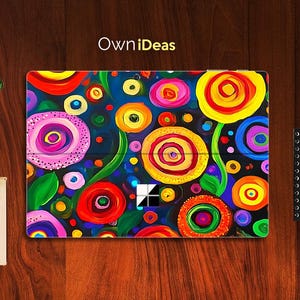Puede incluir: Una funda para portátil colorida con un diseño floral vibrante. La obra de arte incluye flores grandes y estilizadas en tonos rojos, amarillos, rosas y azules sobre un fondo azul oscuro. El texto "Own iDeas" es visible en la parte superior.