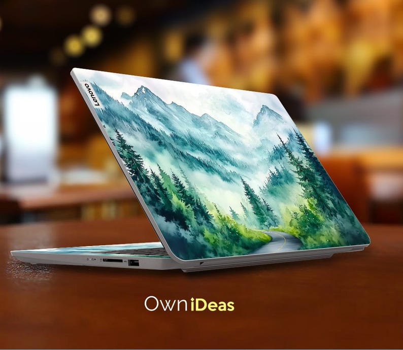 May include: A white laptop with a watercolor design of a mountain range and a winding road through a forest. The laptop has the word "Lenovo" on the back.