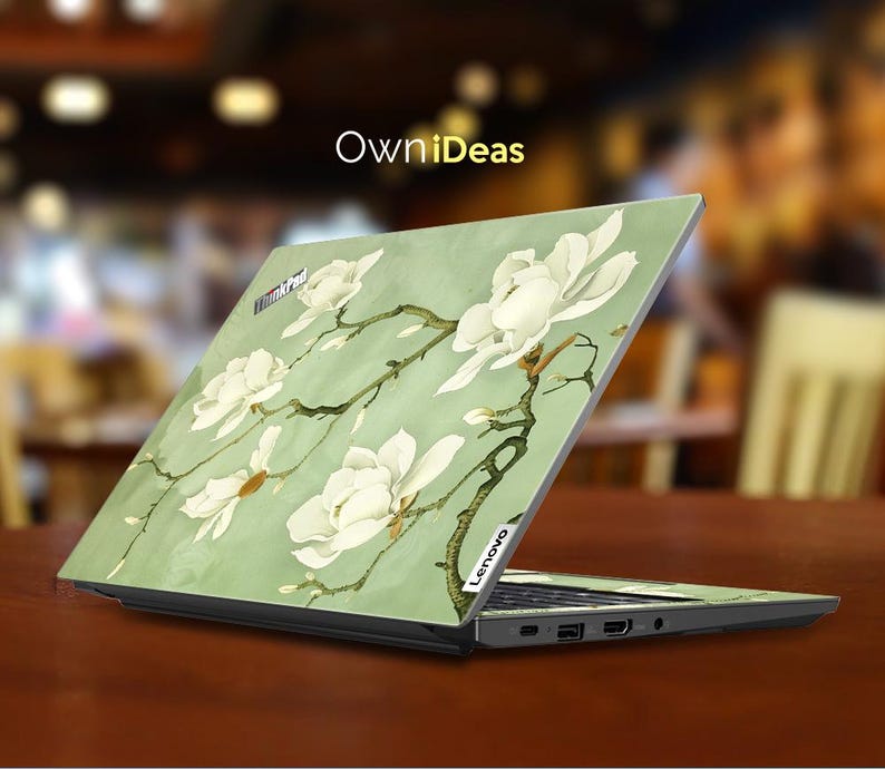 May include: A green laptop skin with a floral design featuring white magnolia blossoms. The skin is designed for a Lenovo laptop. The text "OwnIdeas" is printed on the skin.