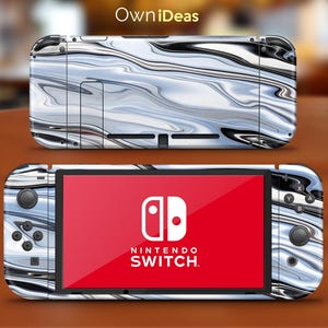 Könnte beinhalten: Eine weiße und schwarze Nintendo Switch Konsolenhaut mit einem flüssigen Marmormuster. Die Haut zeigt ein wirbelndes Muster aus Weiß, Schwarz und Grau. Das Nintendo Switch Logo ist auf dem Bildschirm sichtbar.