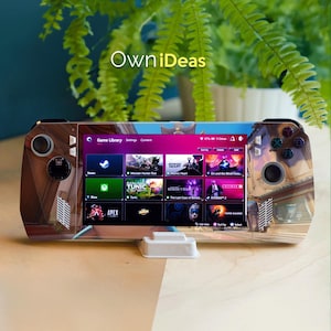 May include: A handheld gaming device with a screen displaying a game library interface. The device has a wooden-like design on the sides and features buttons and joysticks. The screen shows game titles like "Tunic" and "Apex". The text "OwniDeas" is visible.