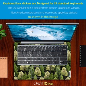 May include: A laptop computer with a green forest design keyboard sticker. The sticker features a repeating pattern of pine trees with green and yellow leaves. The laptop is on a wooden surface.