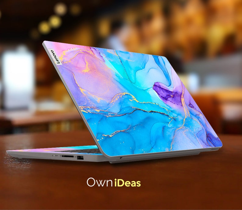 K&ouml;nnte beinhalten: Ein Laptop mit einem abstrakten Design in Blau, Lila und Rosa auf dem Deckel. Das Design verf&uuml;gt &uuml;ber goldene Akzente und &auml;hnelt einem Aquarellbild. Der Laptop ist ge&ouml;ffnet und das Lenovo-Logo ist auf dem Deckel sichtbar.