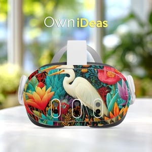 May include: VR headset with a vibrant floral and bird design. The headset features a white egret amidst colorful flowers and foliage. The text "OwniDeas" is displayed at the top. The design includes shades of teal, orange, red, and purple.