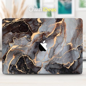 May include: A laptop skin with a marble design featuring black, gray, and gold swirls. The skin has the Apple logo cut out.