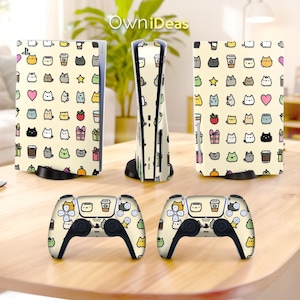 Op de afbeelding: Een gameconsole en controllers met een crèmekleurig ontwerp met een herhalend patroon van cartoonkatten, koffiekopjes, sterren en harten. De console heeft een verticaal ontwerp en de controllers liggen op een houten oppervlak.