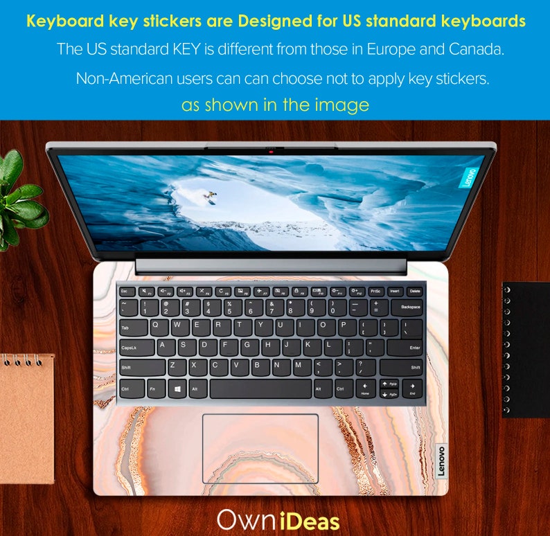 Op de afbeelding: Een laptop met een toetsenbord en een marmerpatroon op de deksel en de palmrest. De laptop is open en het scherm toont een besneeuwde berg sc&egrave;ne. De tekst "OwniDeas" is afgedrukt onder de laptop.