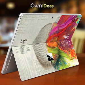 May include: A colourful abstract design of a brain with the words "Left Brain" and "Right Brain" on a laptop skin. The design features a mix of pink, purple, green, yellow, and orange paint splatters.