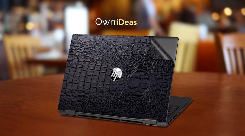 May include: A black laptop with a textured, crocodile-skin-like design on the lid. The HP logo is visible in the center. The laptop is on a brown table, with the text "OwniDeas" in the background.