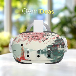 以下が含まれることがあります： 日本のデザインにインスパイアされたVRヘッドセット。ヘッドセットは、着物を着た女性、桜、伝統的な建物の美しいイラストが特徴です。「OwniDeas」というテキストがヘッドセットの上部に表示されています。