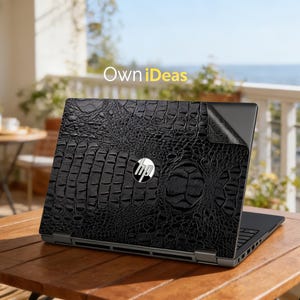 May include: Black laptop skin with a crocodile leather texture, featuring the HP logo. The laptop is placed on a wooden table outdoors, with the text "Own iDeas" in the background.