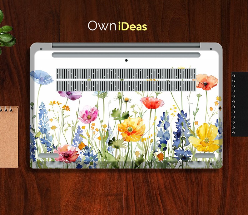 Puede incluir: Un port&aacute;til blanco con un dise&ntilde;o floral en la parte posterior. El dise&ntilde;o presenta flores de acuarela en tonos de azul, rosa, amarillo y rojo. Las flores est&aacute;n dispuestas en una fila horizontal a trav&eacute;s de la parte posterior del port&aacute;til.