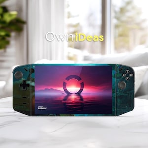 Può includere: Un dispositivo di gioco portatile Lenovo Legion, verde acqua e nero. Lo schermo mostra una scena di tramonto con un design circolare sull'acqua. Il dispositivo ha pulsanti e un joystick su entrambi i lati. Il testo "OwniDeas" è in alto.
