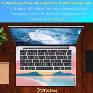 Op de afbeelding: Laptop met een toetsenbord skin met een landschapsontwerp met bergen, water en een zonsondergang. Het toetsenbord heeft zwarte toetsen en witte letters. De tekst op het scherm zegt "Keyboard key stickers are Designed for US standard keyboards".