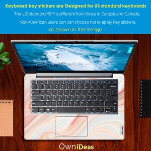 May include: A laptop computer with a white marble-patterned keyboard sticker. The sticker features a swirling pattern of white, peach, and light brown. The laptop is open and the screen shows a snowy mountain scene. The text "OwniDeas" is visible below the laptop.