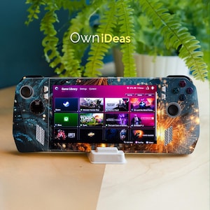 May include: A handheld gaming console with a custom skin featuring a blue and orange firework design. The screen displays a game library with various game icons. The console is resting on a white stand, with the text "OwniDeas" visible.