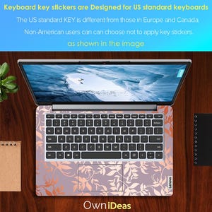 Op de afbeelding: Een Lenovo-laptop met een bloemen toetsenbord skin. De skin heeft een lavendel achtergrond met oranje en witte bladmotieven. Het scherm toont een landschapsafbeelding. Bovenin staat: "Keyboard key stickers are Designed for US standard keyboards."