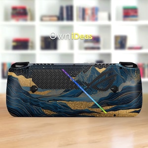 Puede incluir: Una consola de juegos portátil con una piel personalizada que presenta un diseño de paisaje montañoso en tonos de azul y dorado. El diseño incluye una barra de luz de arcoíris y el texto "OwniDeas".