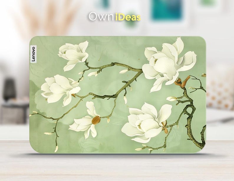 May include: A green laptop skin featuring a white magnolia flower design. The skin has the word "Lenovo" printed on it.