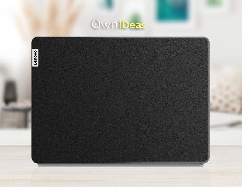 May include: A black Lenovo laptop with a textured lid. The laptop is closed and sitting on a light wood surface.