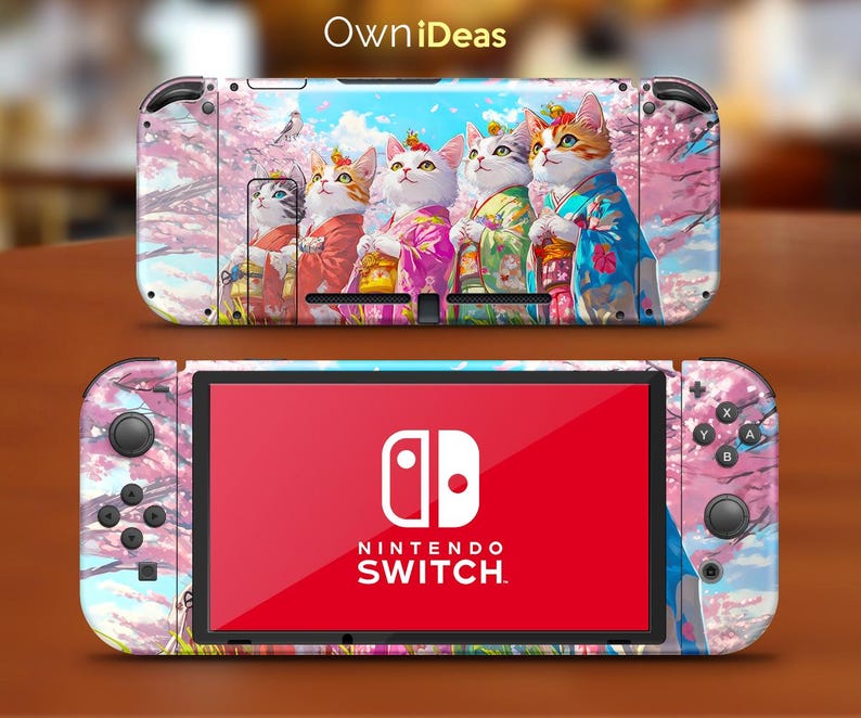 May include: A pink and white Nintendo Switch console skin featuring a design of four cats wearing traditional Japanese clothing in front of a cherry blossom tree. The text "OwnIdeas" is printed at the top of the skin.