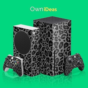 Puede incluir: Dos consolas Xbox Series X negras y grises con un diseño de estampado de leopardo. Las consolas están una al lado de la otra y hay un mando Xbox negro y gris con un diseño de estampado de leopardo delante de ellas. El texto "OwnIdeas" está en la parte superior de la imagen.