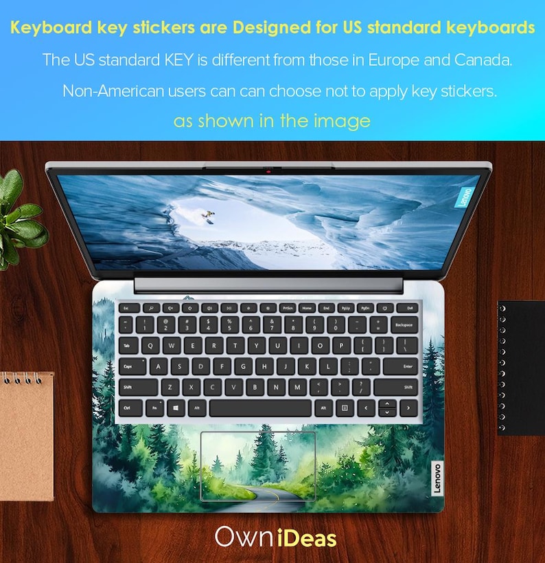 May include: A laptop computer with a green forest scene keyboard sticker. The sticker features a winding road through a forest with trees and a blue sky. The text "Own iDeas" is printed below the keyboard.