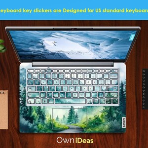 May include: A laptop computer with a green and blue watercolor forest scene keyboard sticker. The sticker features a winding road through the forest. The text "Own iDeas" is printed below the laptop.