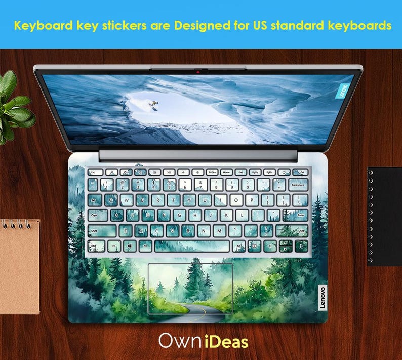 May include: A laptop computer with a green and blue watercolor forest scene keyboard sticker. The sticker features a winding road through the forest. The text "Own iDeas" is printed below the laptop.