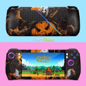 May include: A black handheld gaming console with a Halloween-themed design. The console features a jack-o'-lantern, a ghost, and orange and black accents. The screen displays the game "Stardew Valley".