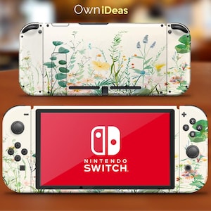 May include: A white Nintendo Switch console with a floral design. The console has a white background with green leaves and pink flowers. The Nintendo Switch logo is visible on the screen.