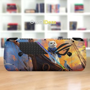 May include: A custom-designed gaming console skin featuring a white cat wearing a blue scarf, perched on a ship's mast. The design includes a sunset backdrop, seagulls, and the ROG logo. The console skin is a protective cover.