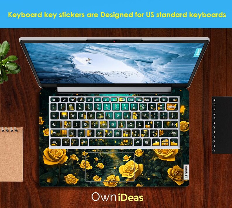 Puede incluir: Un ordenador port&aacute;til con una pegatina de teclado que presenta una escena de bosque oscuro verde y negro con rosas amarillas y luces brillantes. El texto "OwnIdeas" est&aacute; impreso debajo del teclado.