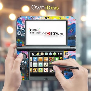 May include: A black Nintendo 3DS XL handheld gaming console with a colourful abstract paint design on the front and back. The console is open and the touch screen is displaying a menu of apps and games. The console is being held by a person's hands, one of which is using the stylus to navigate the menu.