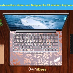 Op de afbeelding: Laptop met toetsenbordstickers. De stickers hebben een bloemenpatroon in roze en oranje tinten. Het scherm toont een landschap. De tekst luidt: "Keyboard key stickers are Designed for US standard keyboards".